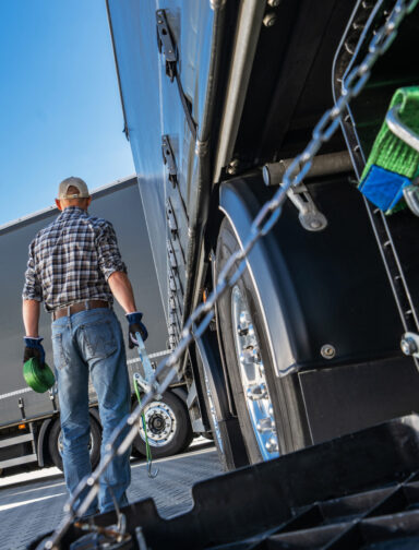 Truck driver performing maintenance on the rear of a truck.