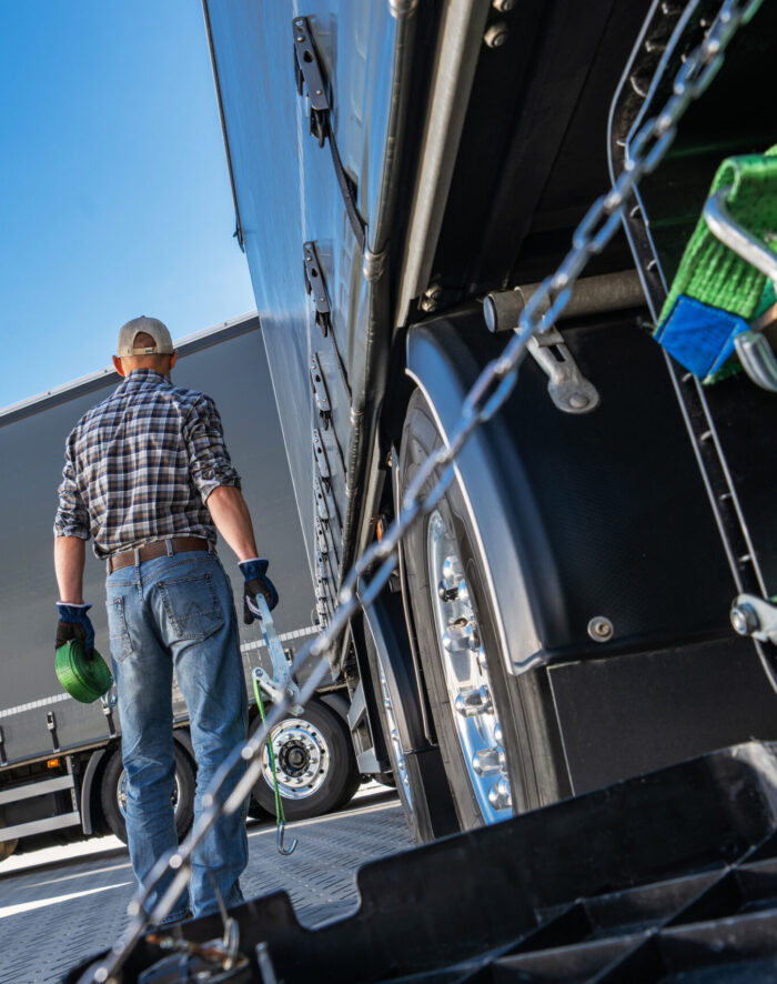 Truck driver performing maintenance on the rear of a truck.