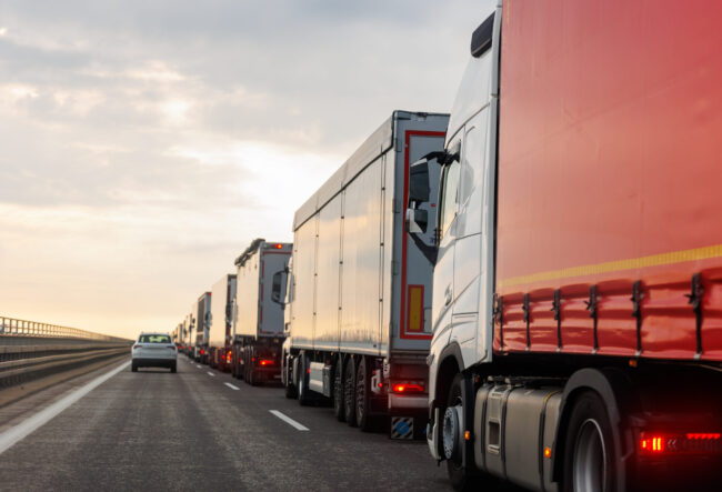 Queue of Trucks on Ukraine-Poland Border traffic jam at Sunset During Protest Roadblock. Business agricultural Logistics blockade action. Cargo lorry semi-trailers stuck.